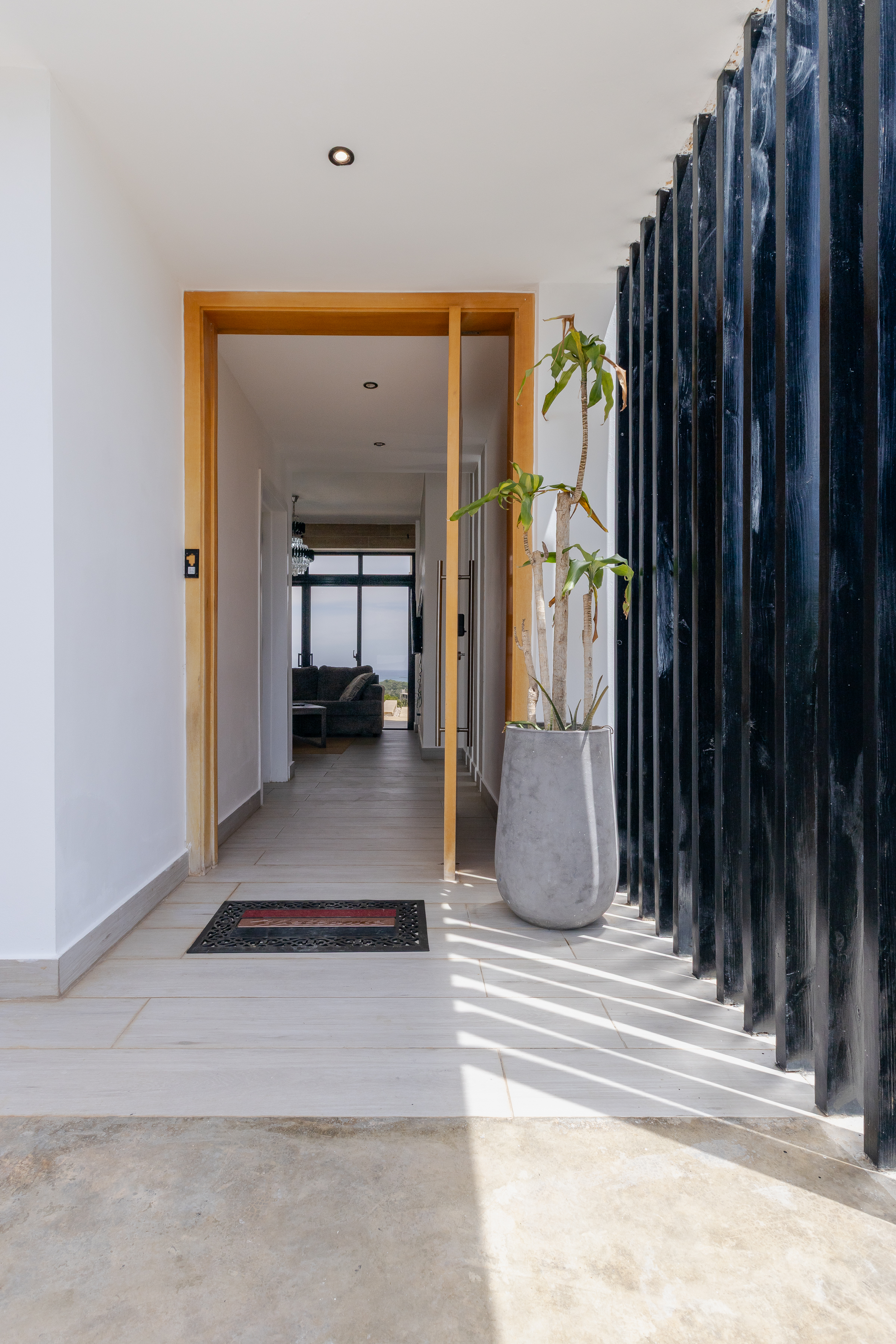 Villa entrance — warm wood door, architectural slats and garden view