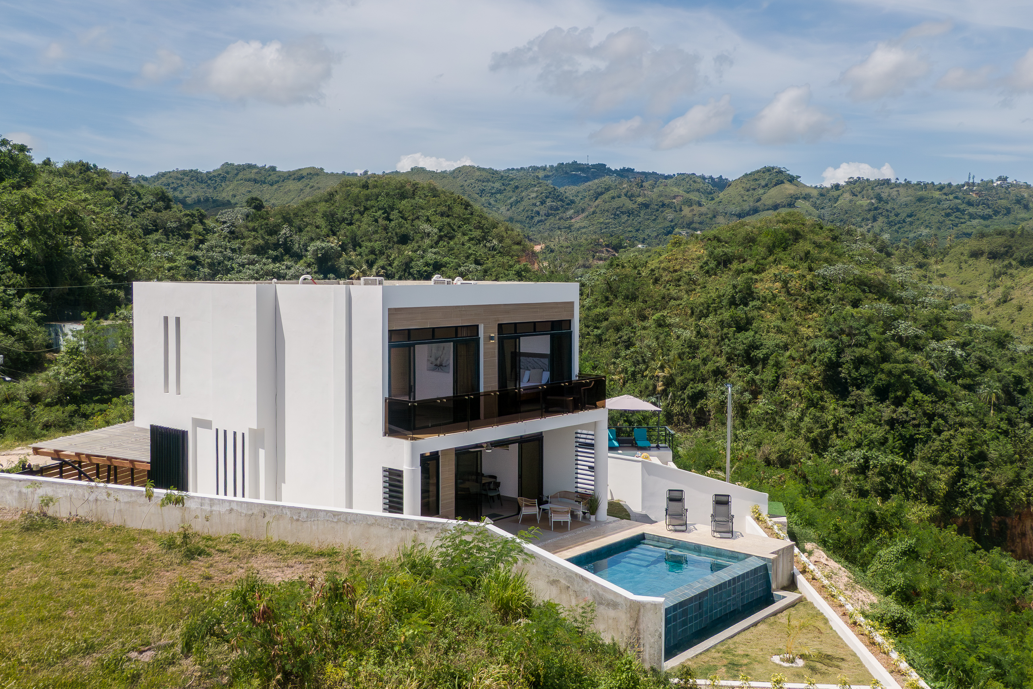 Full villa exterior set against lush green mountain backdrop