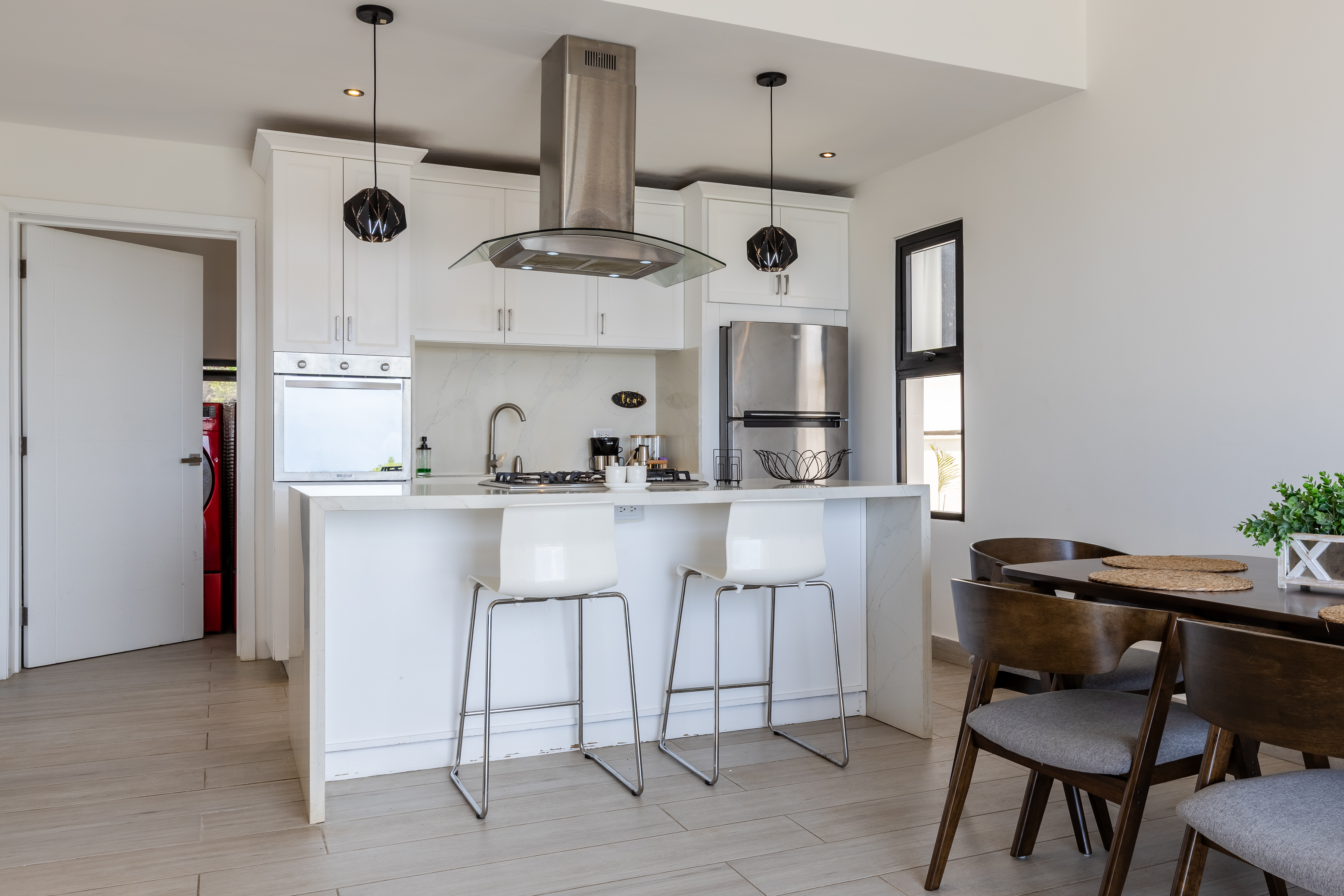 Kitchen with bar stools, pendant lights and dining area