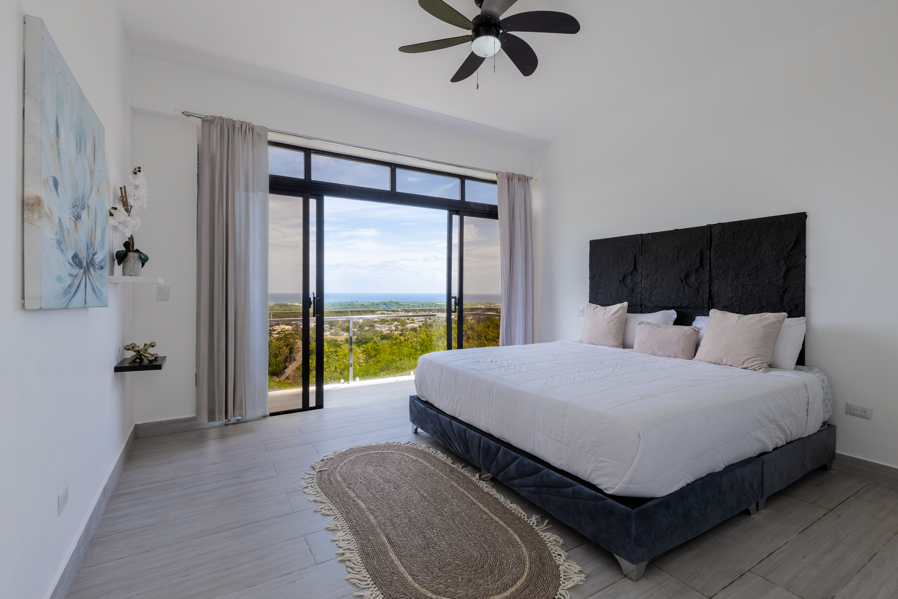 Master bedroom with velvet headboard, artwork and sea view